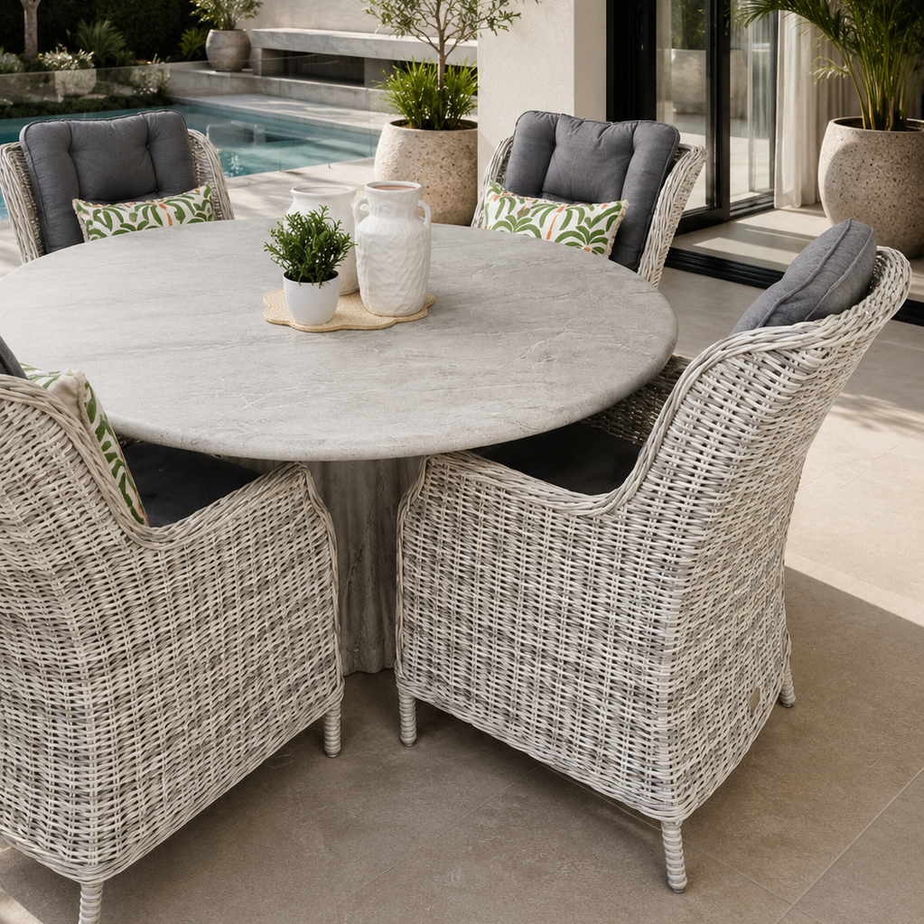 Round outdoor dining setting featuring handwoven all weather wicker armchairs with grey cushions surrounding a sculptural stone-look pedestal table in a high end modern Australian outdoor space. Styled beside a contemporary pool with soft neutral tones, minimalist landscaping and architectural outdoor living details.